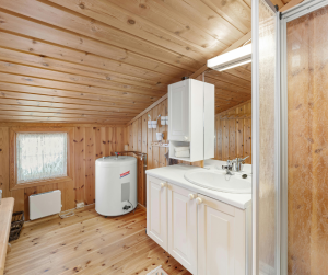 A clean bathroom with wood paneling and a water boiler in the corner