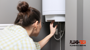 A woman adjusts a water heater in her home.