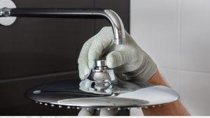 A gloved hand replacing a shower head